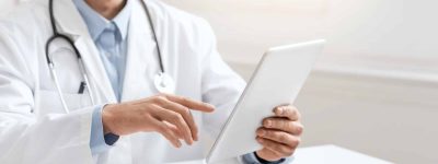 Cheerful doctor consulting patient online via digital tablet